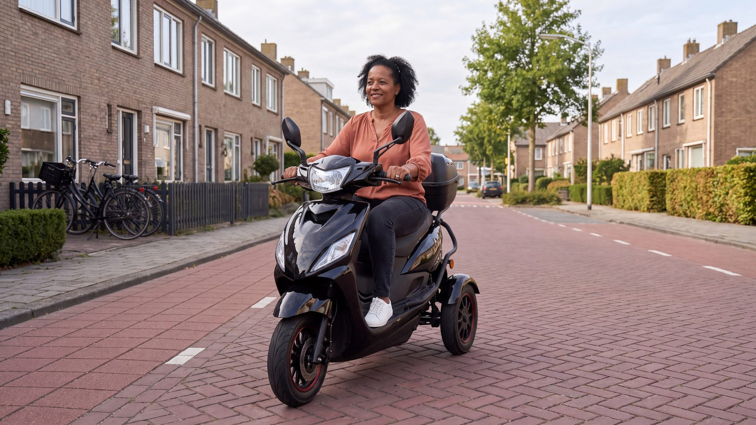 Scooter zonder rijbewijs: vrouw op zwarte IVA T3 2.0 driewieler scootmobiel in Nederlandse woonstraat
